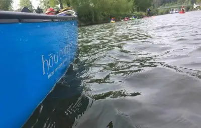 A blue canoe with the word 'hour' visible on its side floating on a river with rippling water.